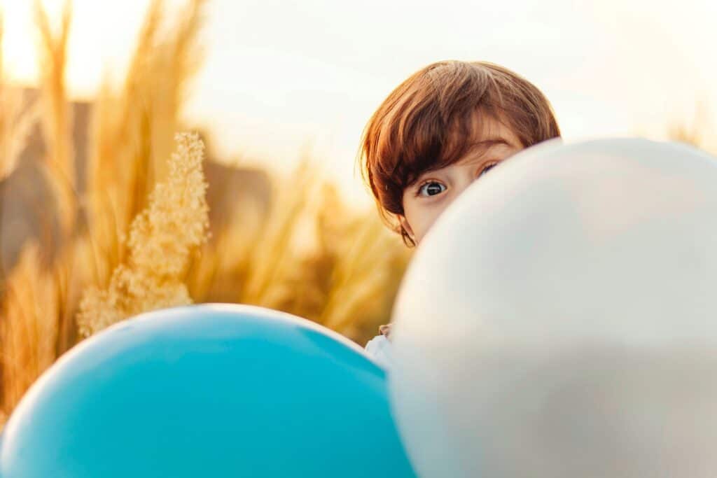 Child hiding behind balloons